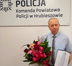 policjant po cywilnemu z bukietem kwiatów i dyplomem