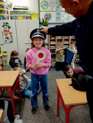 policjant daje dziewczynce policyjną czapkę do przymierzenia