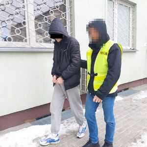 policjant prowadzi zatrzymanego mężczyznę pod komendą