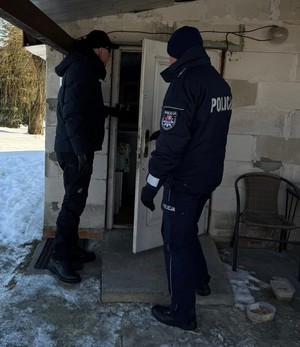 dzielnicowy i pracownik socjalny przed drzwiami