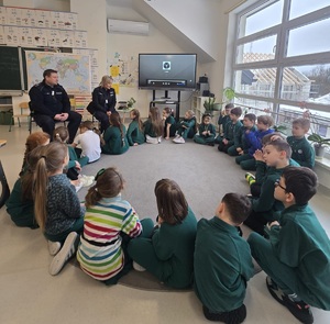 policjanci i dzieci siedzą w kółku