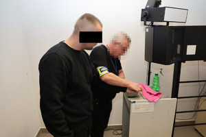 Technik kryminalistyki pobiera odbitki palców od mężczyzny zatrzymanego