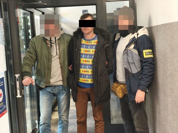 Policjanci prowadzą zatrzymanego mężczyznę