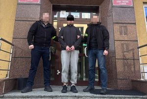 policjanci operacyjni stoją przed prokuraturą z zatrzymanym