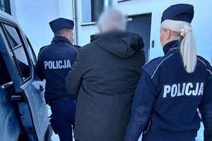 policjanci prowadzą zatrzymanego oszusta