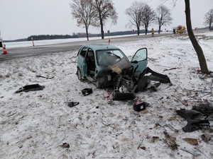 Uszkodzony samochód osobowy po zdarzeniu drogowym w tle stoją pojazdy służb ratunkowych.
