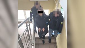 Policjanci prowadza zatrzymanego mężczyznę