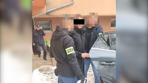 Policjanci prowadza do samochodu zatrzymanego mężczyznę