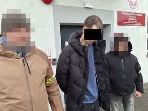 Policjanci prowadzą zatrzymanego mężczyznę.