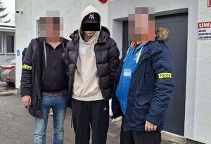 Policjanci prowadzą zatrzymanego mężczyznę.