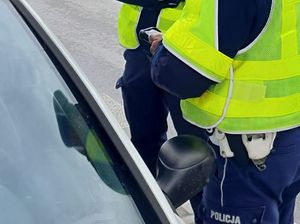 policjant ruchu drogowego przy kontrolowanym aucie