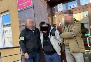 Policjanci prowadzą zatrzymanego mężczyznę.
