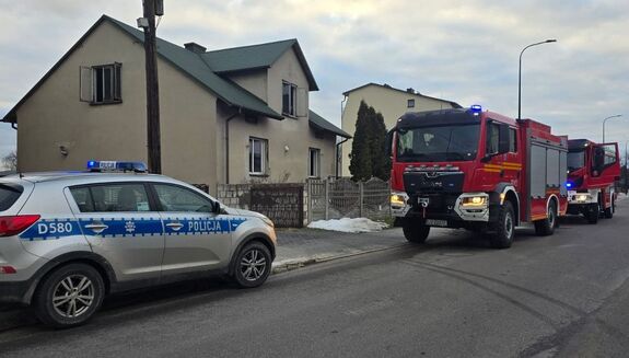 radiowóz i wóz straży pożarnej pod dom, w którym doszło do pożaru