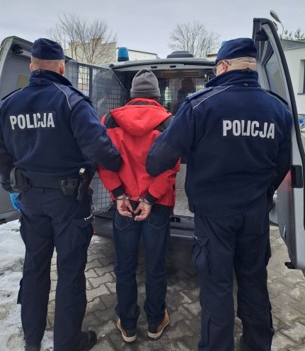 Policjanci przy radiowozie z zatrzymanym