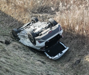 samochód osobowy w rowie, odwrócony do góry kołami