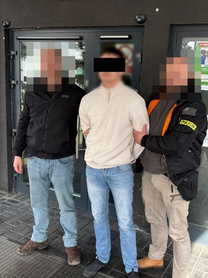 Dwóch nieumundurowanych policjantów i między nimi zatrzymany mężczyzna