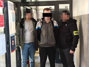 nieumundurowani policjanci z zatrzymanym mężczyzną na korytarzu w komendzie