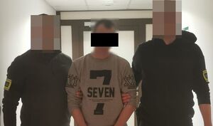 nieumundurowani policjanci z zatrzymanym mężczyzną na korytarzu w komendzie