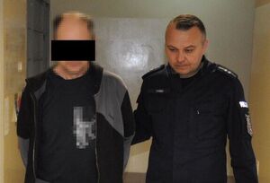 policjant prowadzi zatrzymanego 55-latka