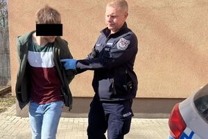 policjant prowadzi do radiowozu zatrzymanego 25-latka