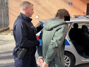 policjant prowadzi do radiowozu zatrzymanego 25-latka