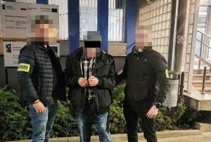 Policjanci prowadzą zatrzymanego mężczyznę.