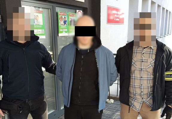 Policjanci prowadzą zatrzymanego mężczyznę.