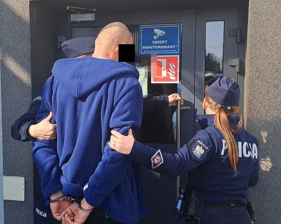 policjanci prowadza zatrzymanego mężczyznę