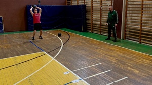 uczeń wykonuje rzut piłką lekarską na sali gimnastycznej