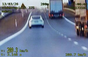 Ujęcie z wideorejestratora na lewym pasie drogi s17 biała tesla i napis 209 km na godzinę na prawym pasie dwie ciężarówki.