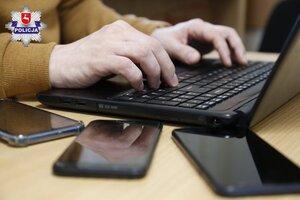 widoczna dłoń przy komputerze i telefony leżące obok