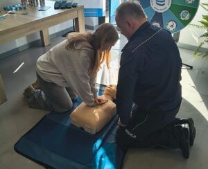 policjant i osobą ćwicząca na fantomie masaż serca
