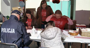 policjant siedzi przy stoisku z rejestracją dawców szpiku