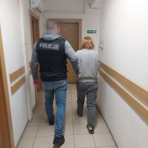 policjant prowadzi zatrzymaną kobietę