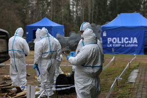 Policjanci ubrani w strój ochronny zabezpieczają ślady na miejscu wypadku.