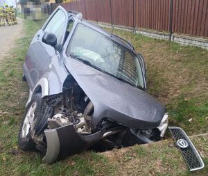 uszkodzony samochód w przydrożnym rowie, w tle strażacy