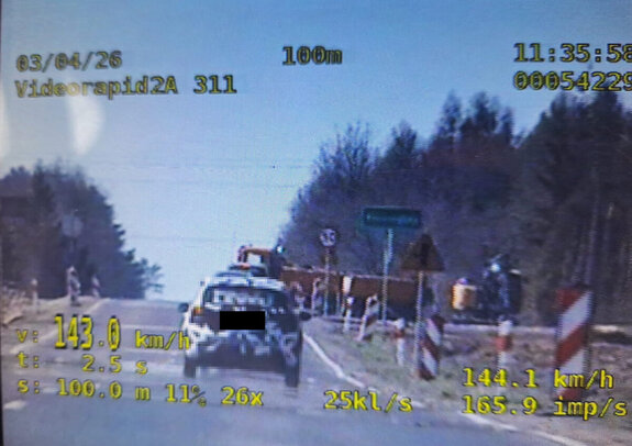 ekran videorejestratora na którym widać pojazd osobowy, któremu zmierzono prędkość oraz w tle droga znaki drogowe i inne pojazdy, na dole wyświetlone są parametry urządzenia pomiarowego w tym wynik pomiaru 143 kh/h