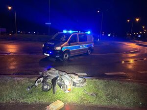 przewrócony motorower na drodze, obok radiowóz