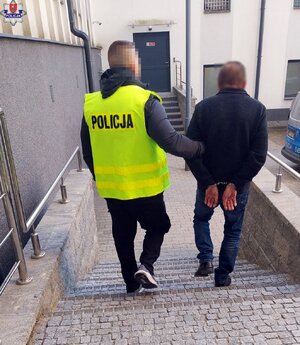 policjant prowadzi zatrzymanego schodami