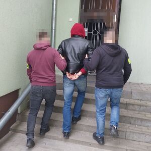 policjanci prowadzą zatrzymanego mężczyznę