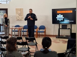 Policjant podczas prelekcji w szkole trzyma w ręku mikrofon