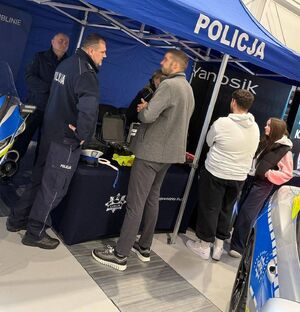 policjant przy stoisku rozmawia z zainteresowanymi osobami