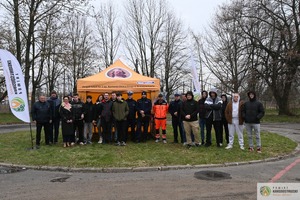 Grupa osób stojąca na zewnątrz wraz z policjantami i ratownikiem medycznym przy namiocie promocyjnym szkoły