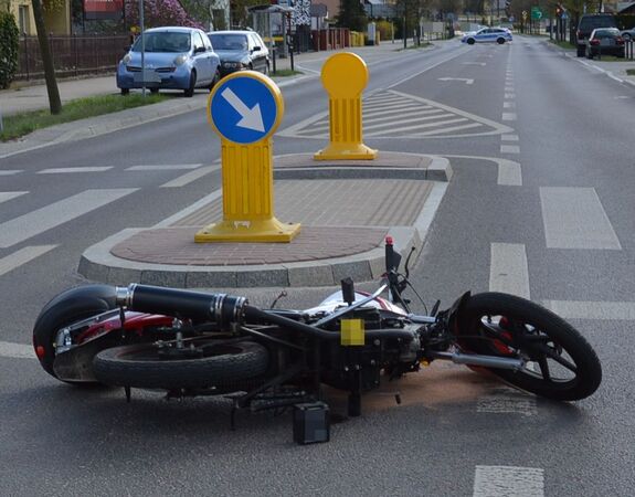 motorower leżący na jezdni, w dalszym planie radiowóz