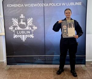 uczennica oddziału o profilu mundurowych trzyma plakat promujący policję
