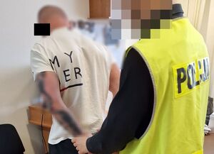 Policjant zakłada kajdanki zatrzymanemu mężczyźnie.