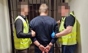 Policjanci prowadzą zatrzymanego mężczyznę.
