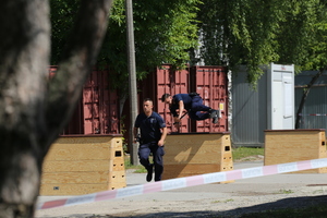 Policjanci podczas zawodów przeskakują przez skrzynię.