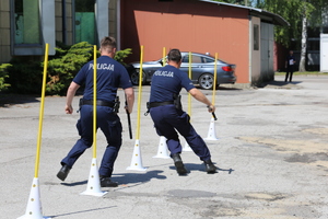 Policjanci biegną między pachołkami.