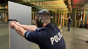 Policjant strzela do tarczy strzeleckiej.